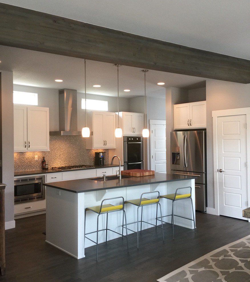 Design ideas for a transitional kitchen in Denver with a single-bowl sink, recessed-panel cabinets, white cabinets, quartz benchtops, stainless steel appliances, medium hardwood floors, grey splashback and glass tile splashback.