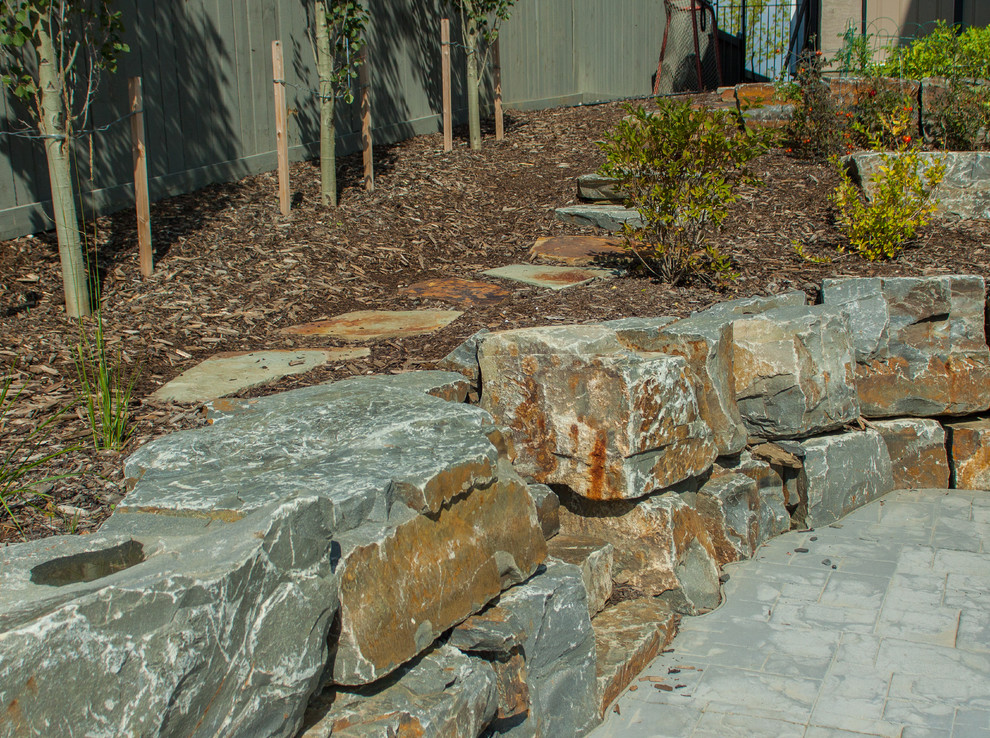This is an example of a large traditional partial sun backyard stone retaining wall landscape in Edmonton for summer.