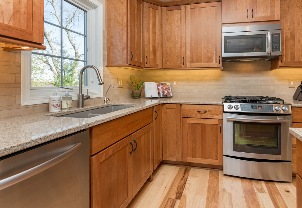 Inspiration for a mid-sized transitional l-shaped light wood floor open concept kitchen remodel with an undermount sink, recessed-panel cabinets, medium tone wood cabinets, quartz countertops, beige backsplash, stone tile backsplash, stainless steel appliances and an island