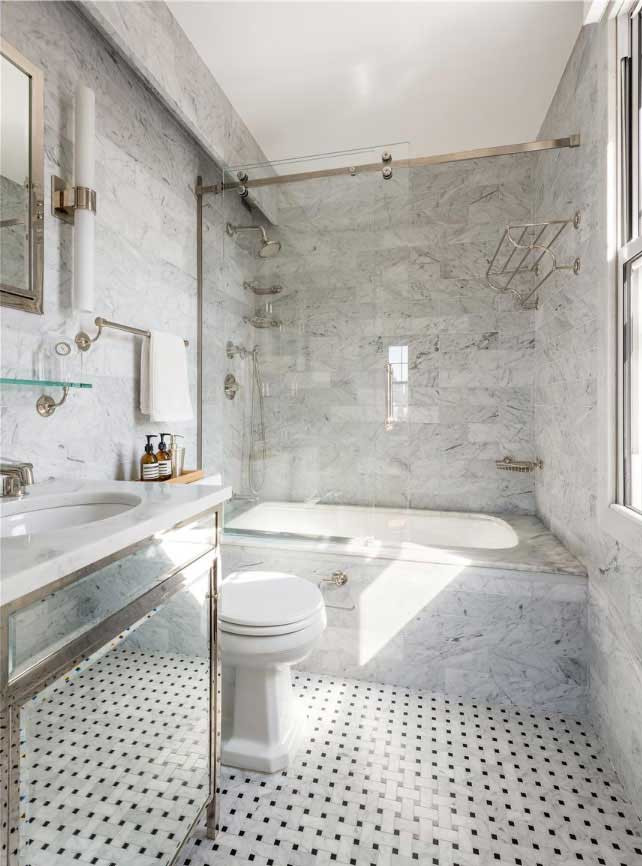На фото: главная ванная комната среднего размера в классическом стиле с стеклянными фасадами, ванной в нише, душем над ванной, унитазом-моноблоком, серой плиткой, мраморной плиткой, серыми стенами, мраморным полом, врезной раковиной, мраморной столешницей, черным полом, душем с раздвижными дверями, белой столешницей, сиденьем для душа, тумбой под одну раковину и напольной тумбой