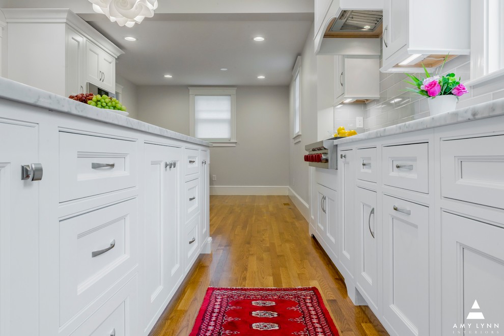 Example of a mid-sized transitional l-shaped medium tone wood floor and red floor eat-in kitchen design in Boston with an undermount sink, beaded inset cabinets, white cabinets, marble countertops, gray backsplash, porcelain backsplash, paneled appliances, an island and yellow countertops