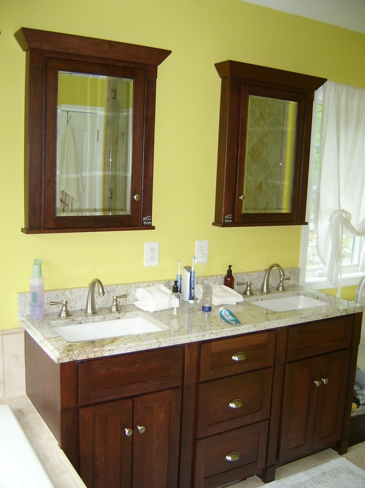 This is an example of a large transitional master bathroom in New York with an undermount sink, recessed-panel cabinets, dark wood cabinets, granite benchtops, a drop-in tub, beige tile, porcelain tile, yellow walls, porcelain floors and beige floor.