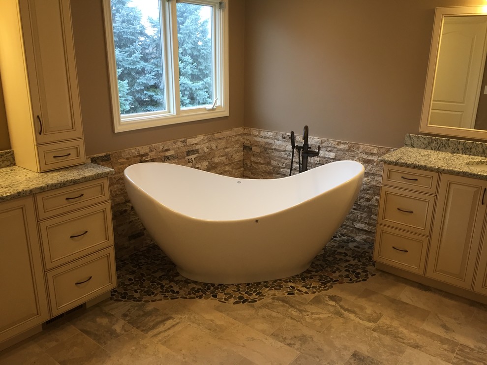 This is an example of a large transitional master bathroom in Detroit with granite benchtops, stone tile, brown walls, an undermount sink, a hinged shower door, recessed-panel cabinets, beige cabinets, a freestanding tub and an alcove shower.