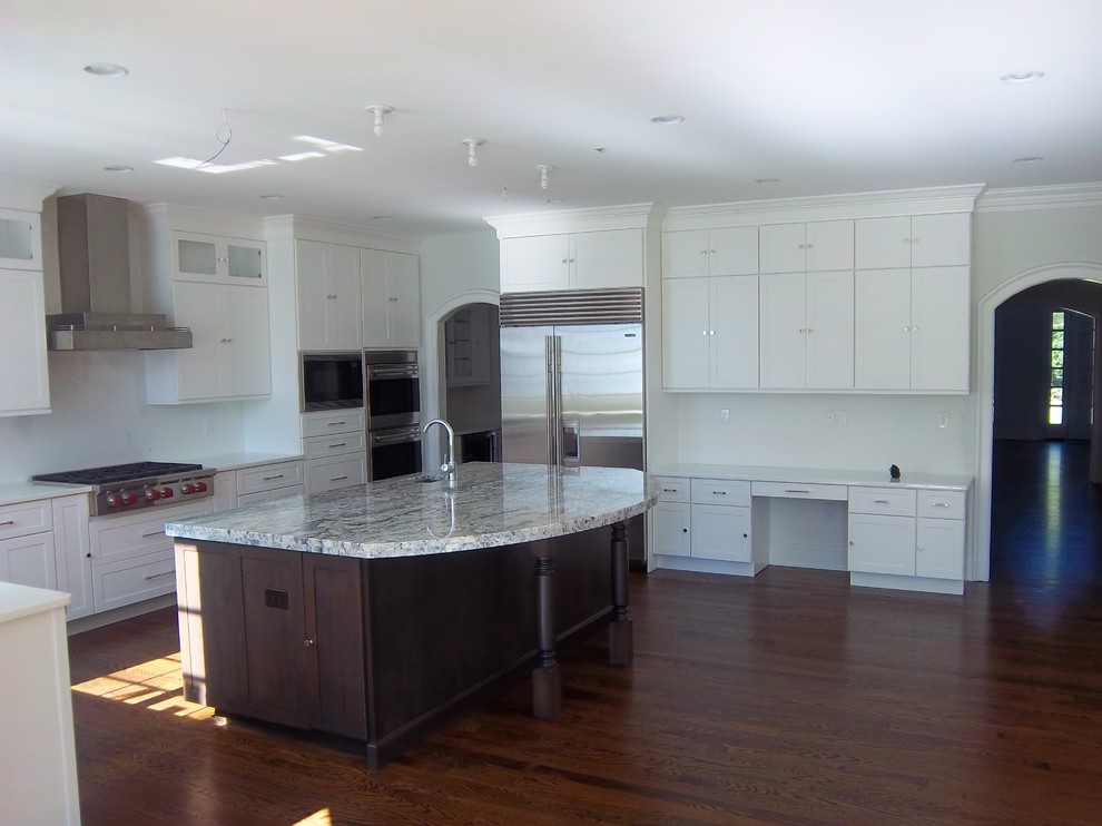 Eat-in kitchen - large transitional u-shaped dark wood floor and brown floor eat-in kitchen idea with shaker cabinets, white cabinets, white backsplash, stainless steel appliances, an island, an undermount sink, solid surface countertops and white countertops