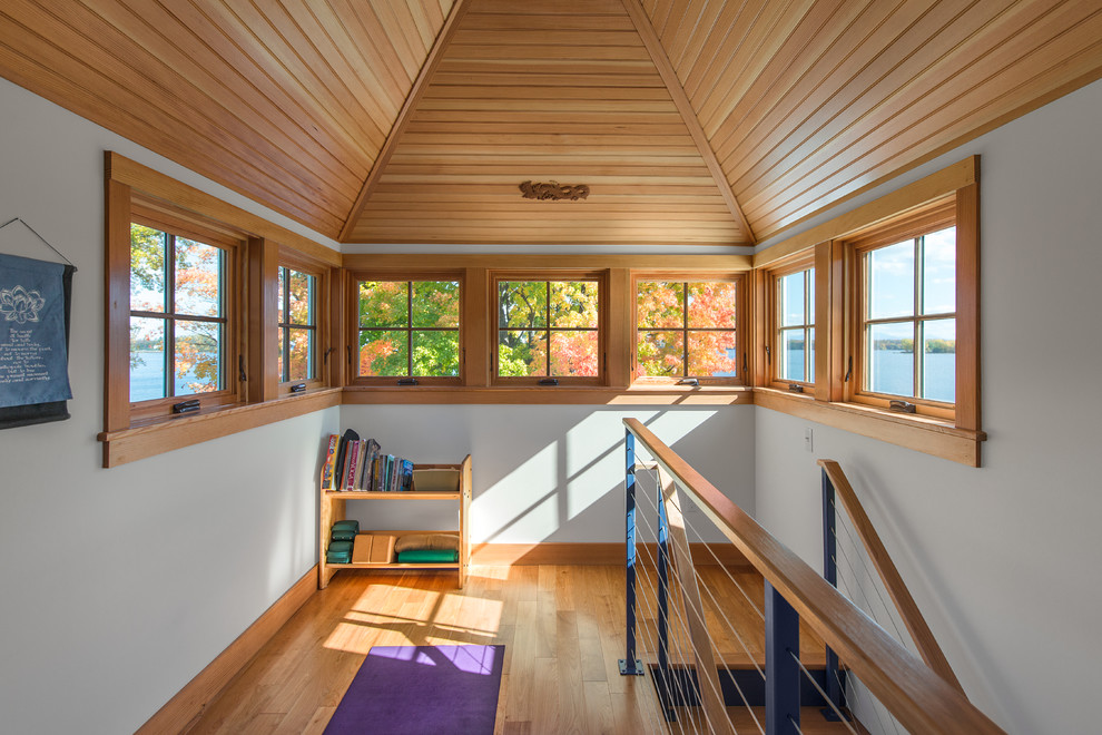 Inspiration for a small industrial home yoga studio in Burlington with white walls and light hardwood floors.