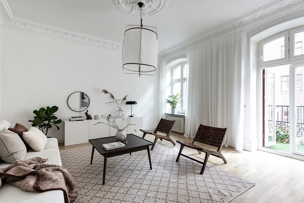 Photo of a scandinavian living room in Gothenburg with white walls, light hardwood floors and beige floor.