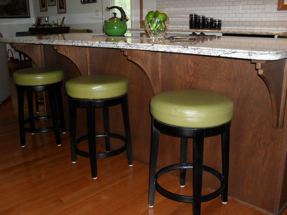 Large transitional medium tone wood floor open concept kitchen photo with white cabinets, white backsplash, black appliances, an island, a farmhouse sink, recessed-panel cabinets and subway tile backsplash