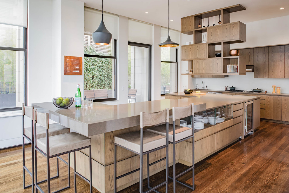 This is an example of a large contemporary u-shaped kitchen in New York with flat-panel cabinets, medium wood cabinets, quartz benchtops, white splashback, glass sheet splashback, stainless steel appliances, with island, brown floor, beige benchtop and dark hardwood floors.