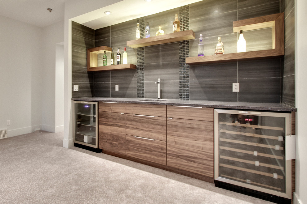 Inspiration for a mid-sized transitional single-wall wet bar in Calgary with an undermount sink, flat-panel cabinets, medium wood cabinets, solid surface benchtops, grey splashback, porcelain splashback, concrete floors and grey floor.