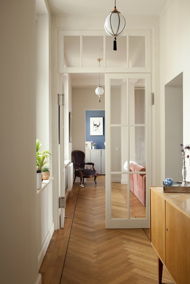This is an example of a traditional hallway in Dresden with white walls and medium hardwood floors.