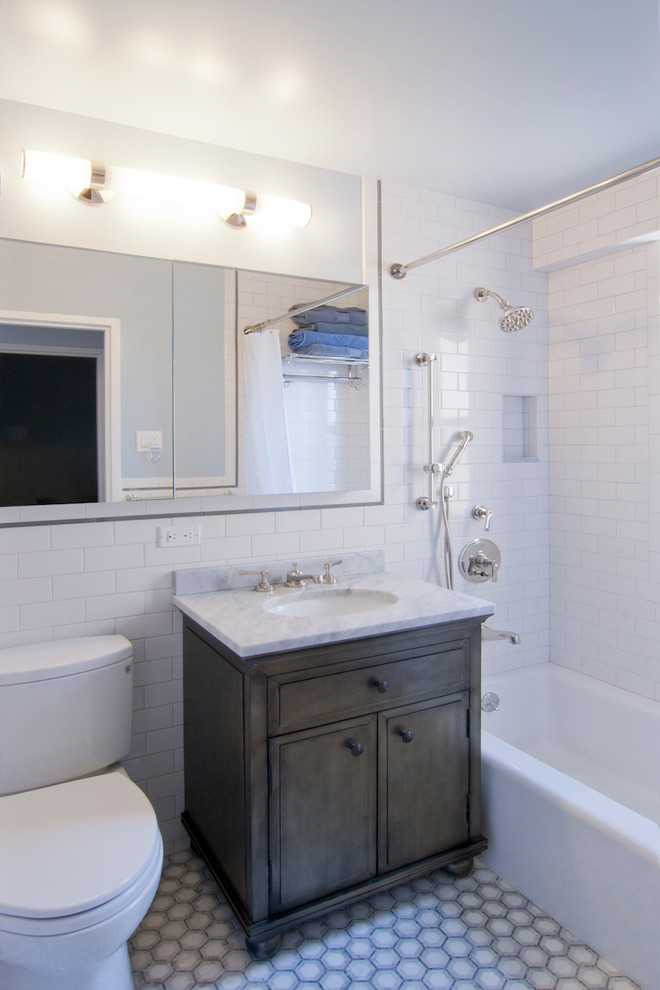 Photo of a small contemporary 3/4 bathroom in New York with furniture-like cabinets, dark wood cabinets, an alcove tub, a shower/bathtub combo, a two-piece toilet, white tile, grey walls, ceramic floors, an undermount sink, marble benchtops, multi-coloured floor, a shower curtain and grey benchtops.