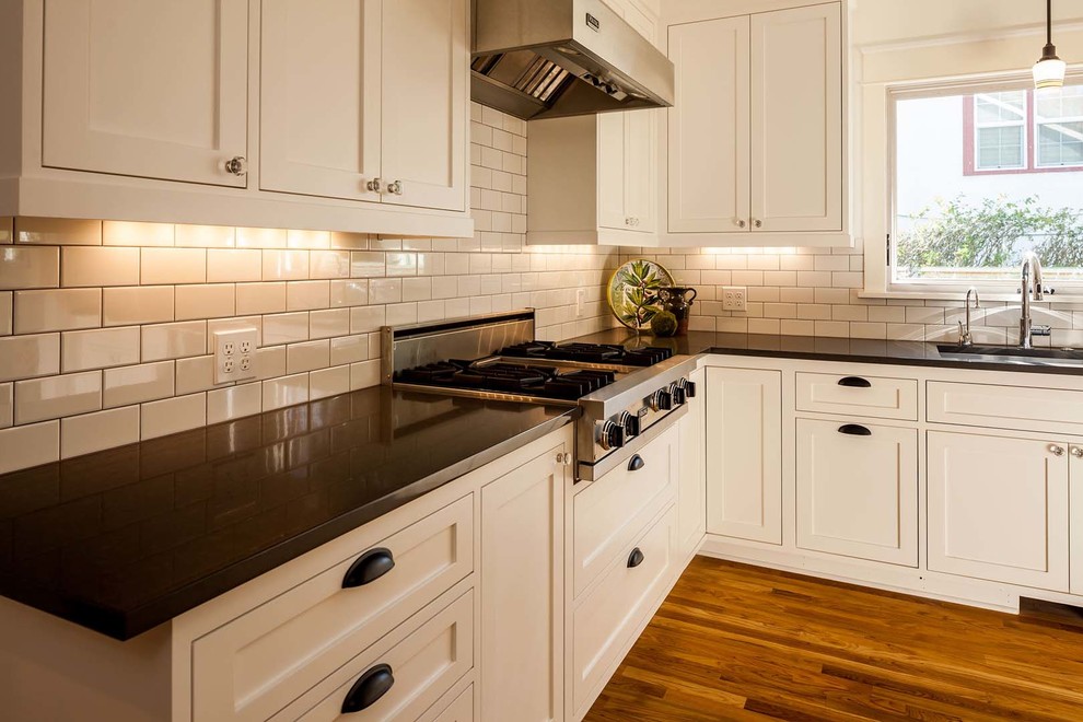 Large transitional dark wood floor kitchen photo with a drop-in sink, recessed-panel cabinets, white cabinets, granite countertops, white backsplash, subway tile backsplash, stainless steel appliances and an island