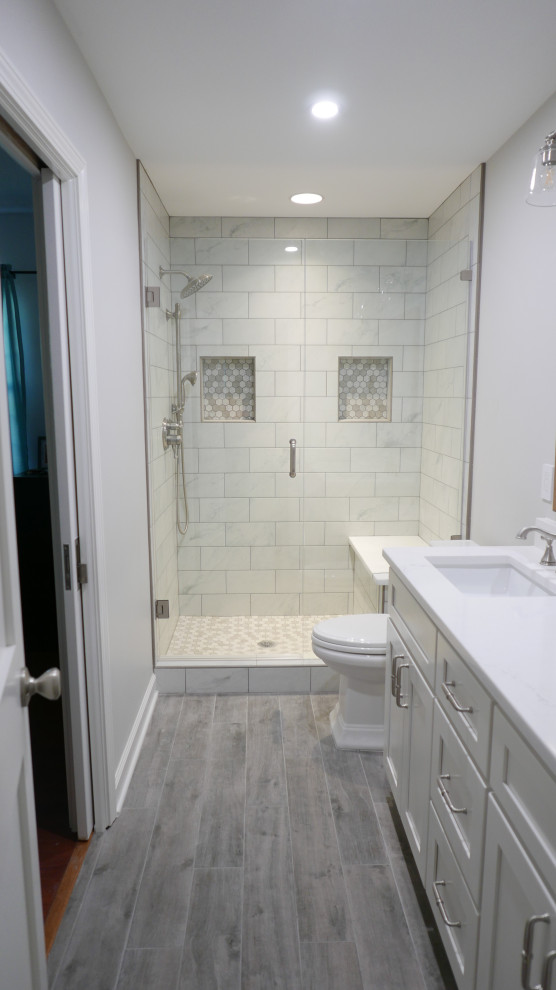 Bathroom - mid-sized transitional kids' white tile and porcelain tile porcelain tile, gray floor and double-sink bathroom idea in Other with shaker cabinets, white cabinets, a two-piece toilet, gray walls, an undermount sink, quartz countertops, a hinged shower door, white countertops and a built-in vanity