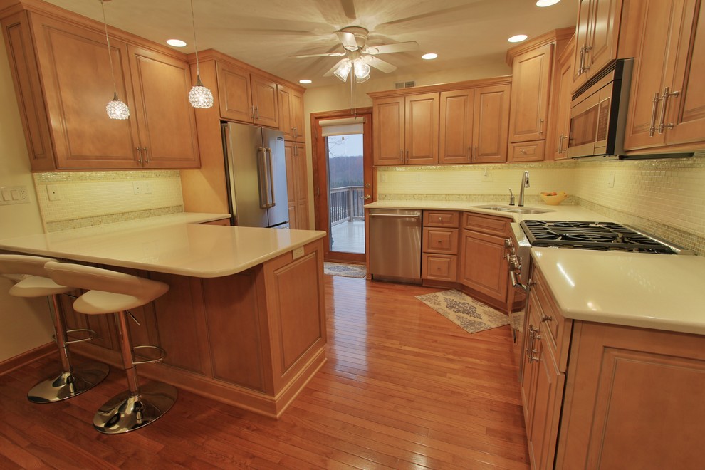 Eat-in kitchen - mid-sized medium tone wood floor eat-in kitchen idea with an undermount sink, medium tone wood cabinets, quartzite countertops, beige backsplash, ceramic backsplash and stainless steel appliances