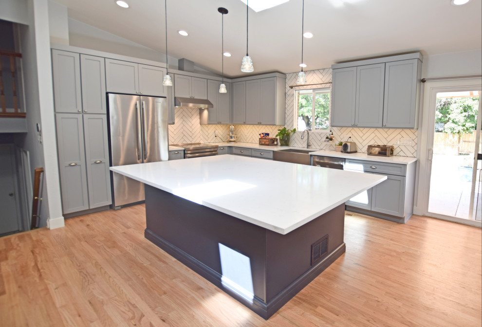 Design ideas for a mid-sized transitional l-shaped open plan kitchen in Denver with a farmhouse sink, shaker cabinets, grey cabinets, quartz benchtops, white splashback, stainless steel appliances, with island, white benchtop and vaulted.