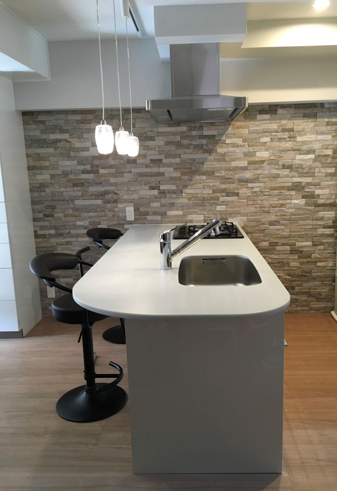 Inspiration for a mid-sized modern single-wall open plan kitchen in Fukuoka with an undermount sink, white cabinets, solid surface benchtops, white splashback, shiplap splashback, black appliances, light hardwood floors, a peninsula, beige floor and green benchtop.