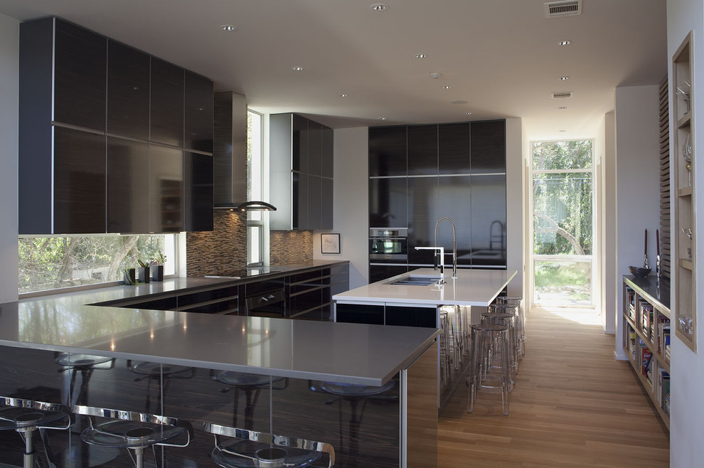 Design ideas for a large contemporary u-shaped eat-in kitchen in Austin with flat-panel cabinets, black cabinets, multi-coloured splashback, a triple-bowl sink, quartz benchtops, mosaic tile splashback, stainless steel appliances, medium hardwood floors and with island.
