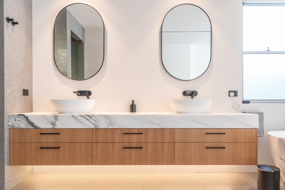 Contemporary master bathroom in Sunshine Coast with flat-panel cabinets, medium wood cabinets, a freestanding tub, a vessel sink, marble benchtops, grey benchtops, a double vanity and a floating vanity.