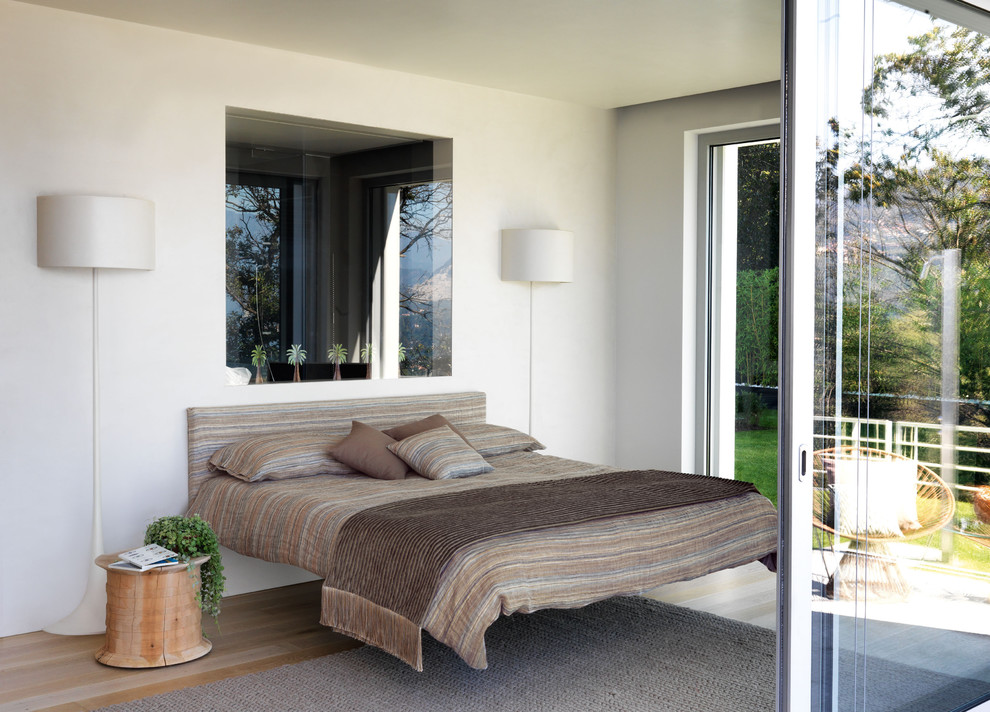 Design ideas for a mid-sized contemporary guest bedroom in Paris with white walls and light hardwood floors.