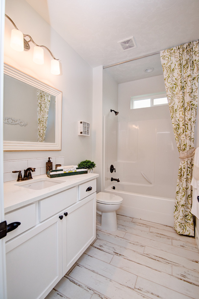 Mid-sized country kids bathroom in Seattle with shaker cabinets, white cabinets, a shower/bathtub combo, a two-piece toilet, white tile, ceramic tile, white walls, ceramic floors, an undermount sink, quartzite benchtops, white floor and a shower curtain.