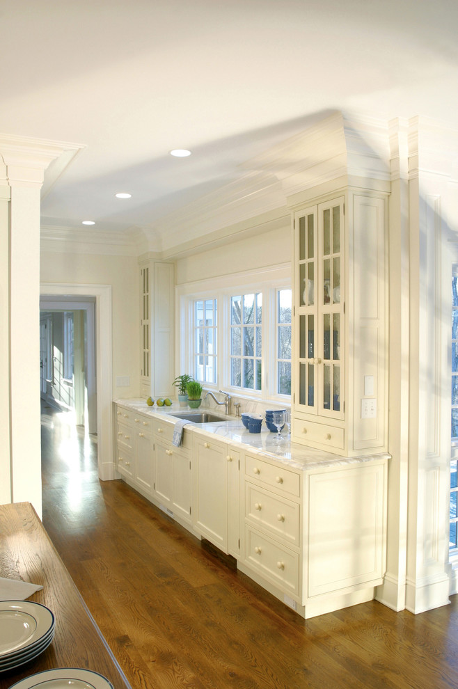Example of a large transitional galley medium tone wood floor and brown floor open concept kitchen design with an undermount sink, glass-front cabinets, white cabinets, stainless steel appliances and no island