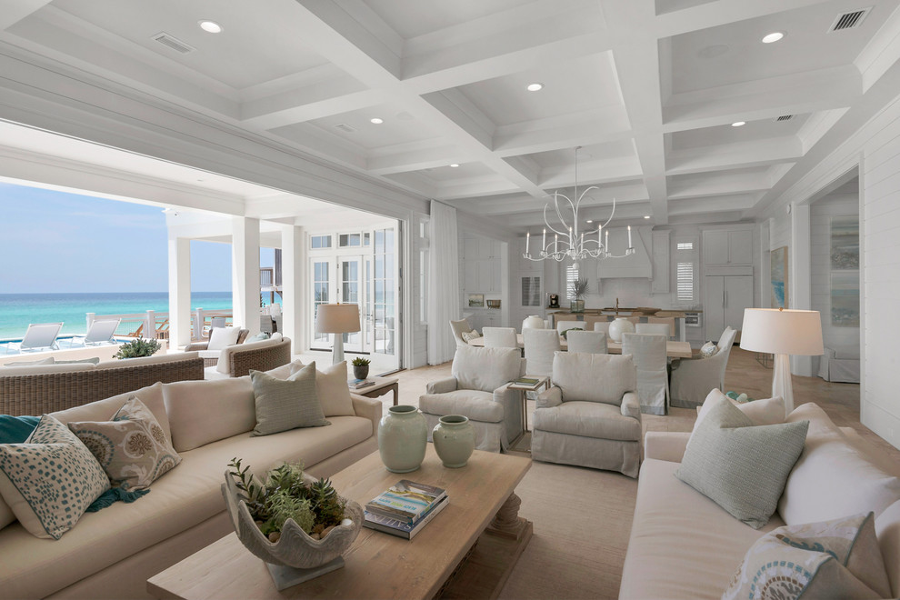 Photo of an expansive beach style open concept living room in Miami with white walls, a standard fireplace, a tile fireplace surround, a wall-mounted tv and travertine floors.