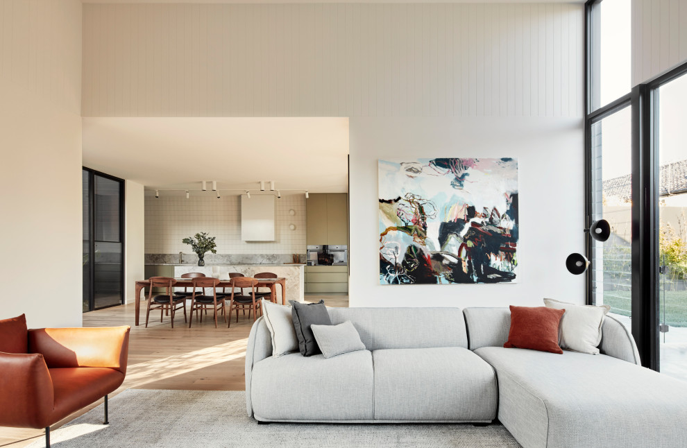 This is an example of a large contemporary open concept family room in Melbourne with white walls, light hardwood floors, a hanging fireplace and beige floor.