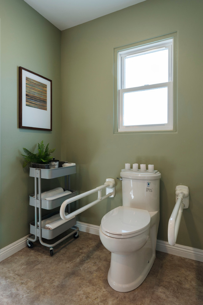 This is an example of a mid-sized transitional powder room in San Diego with a one-piece toilet, green walls and vinyl floors.