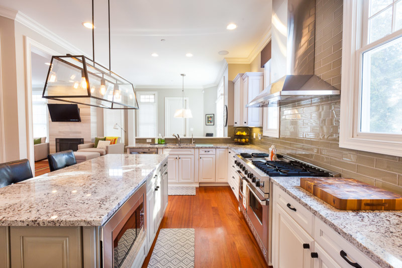 This is an example of a large contemporary u-shaped open plan kitchen in Chicago with an undermount sink, raised-panel cabinets, white cabinets, granite benchtops, green splashback, glass tile splashback, stainless steel appliances, medium hardwood floors and with island.