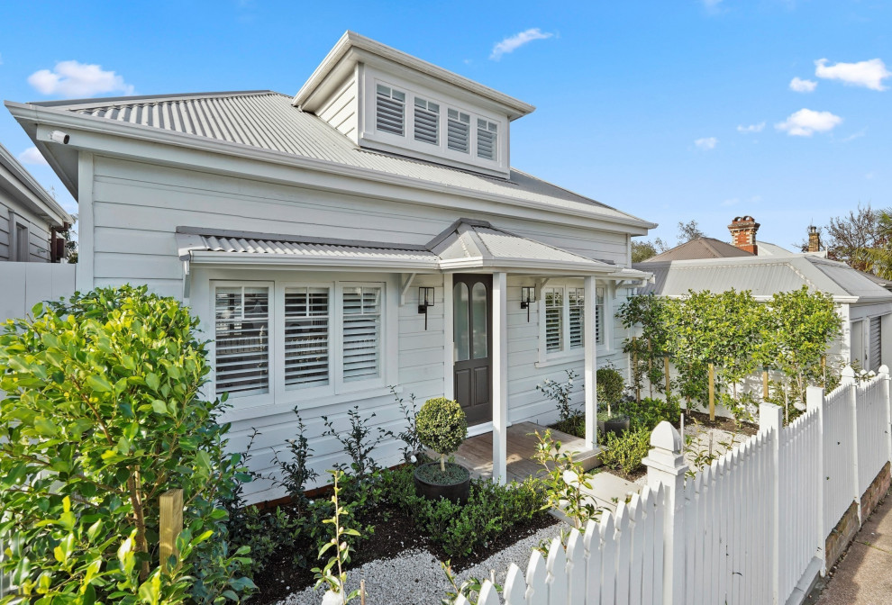 This is an example of a medium sized and white victorian detached house in Auckland with three floors.