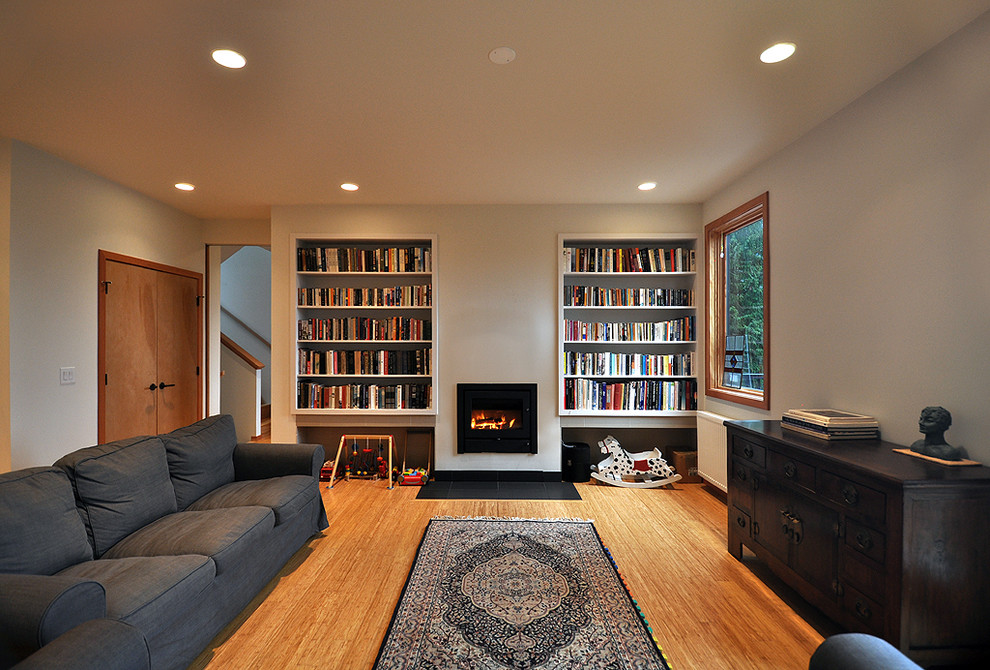 Design ideas for a large contemporary open concept living room in Vancouver with white walls, bamboo floors, a standard fireplace, a library and no tv.