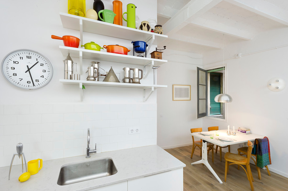 Photo of a small contemporary l-shaped eat-in kitchen in Barcelona with a single-bowl sink, flat-panel cabinets, white cabinets, medium hardwood floors and no island.