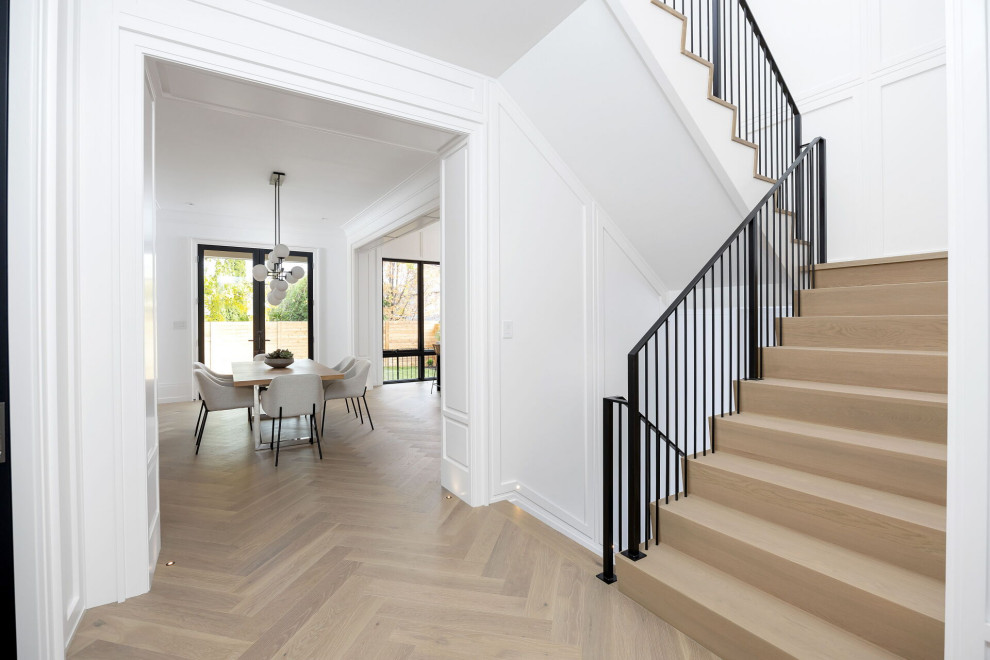 Modelo de escalera en U clásica renovada de tamaño medio con escalones de madera, contrahuellas de madera pintada, barandilla de metal y panelado