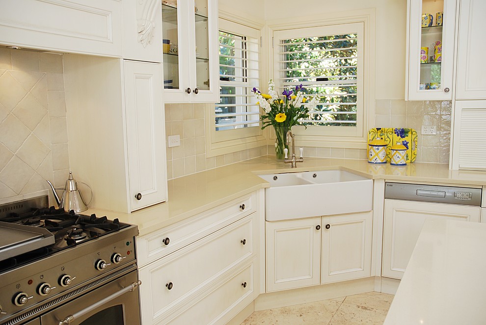 This is an example of a large traditional l-shaped eat-in kitchen in Sydney with a farmhouse sink, shaker cabinets, white cabinets, quartz benchtops, beige splashback, ceramic splashback, stainless steel appliances, travertine floors and with island.