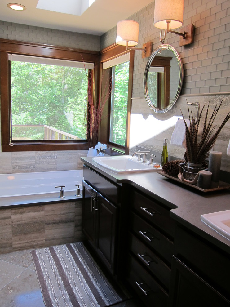 Photo of a large contemporary master bathroom in Seattle with shaker cabinets, dark wood cabinets, a corner tub, an open shower, gray tile, glass tile, grey walls, limestone floors, a drop-in sink and engineered quartz benchtops.