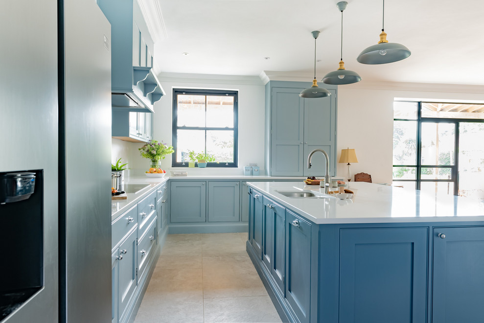 Large beach style u-shaped eat-in kitchen in Surrey with shaker cabinets, blue cabinets, quartzite benchtops, stainless steel appliances, ceramic floors, with island and white benchtop.