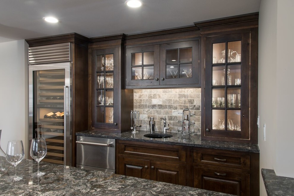 Photo of a large traditional galley seated home bar in St Louis with raised-panel cabinets, medium wood cabinets, solid surface benchtops, multi-coloured splashback, dark hardwood floors and subway tile splashback.
