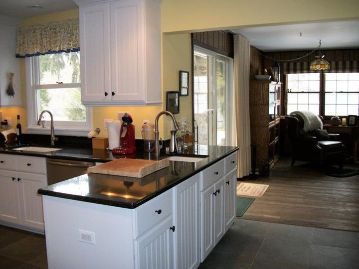This is an example of a small country u-shaped eat-in kitchen in Chicago with an undermount sink, white cabinets, granite benchtops, yellow splashback, stainless steel appliances and slate floors.