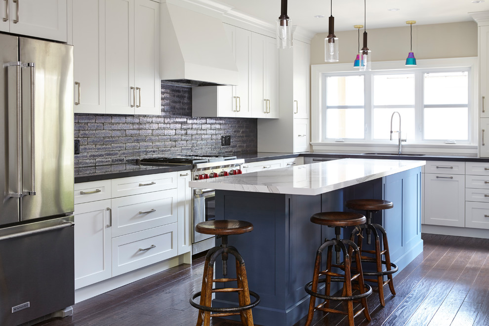 Inspiration for a mid-sized eclectic l-shaped medium tone wood floor and brown floor eat-in kitchen remodel in Toronto with an undermount sink, shaker cabinets, blue cabinets, quartz countertops, black backsplash, ceramic backsplash, stainless steel appliances and an island