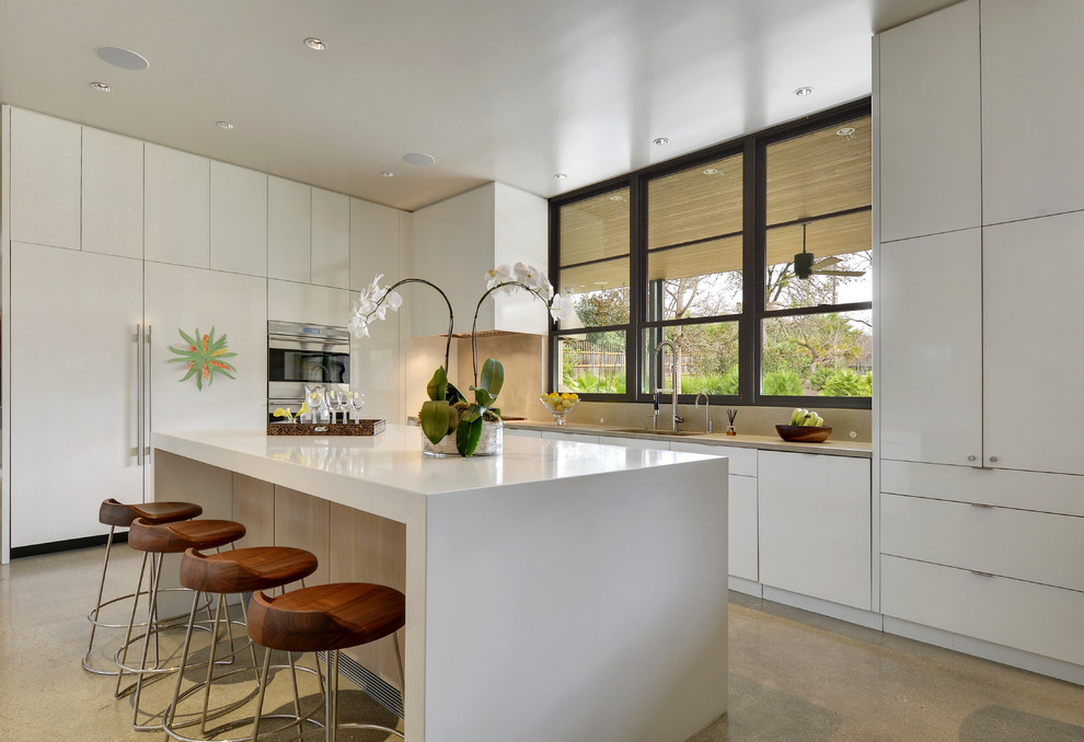 Photo of a contemporary l-shaped kitchen in Austin with flat-panel cabinets, white cabinets, beige splashback, stone slab splashback, carpet and with island.