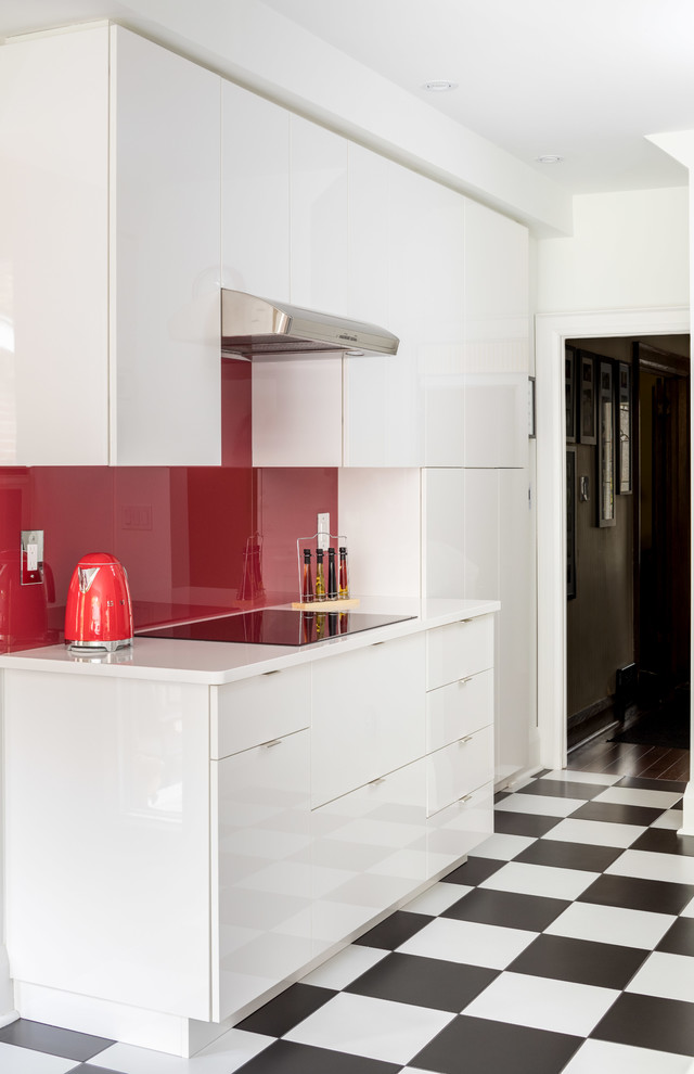 This is an example of a small contemporary galley eat-in kitchen in Toronto with an undermount sink, flat-panel cabinets, white cabinets, quartz benchtops, red splashback, glass sheet splashback, stainless steel appliances, porcelain floors and no island.