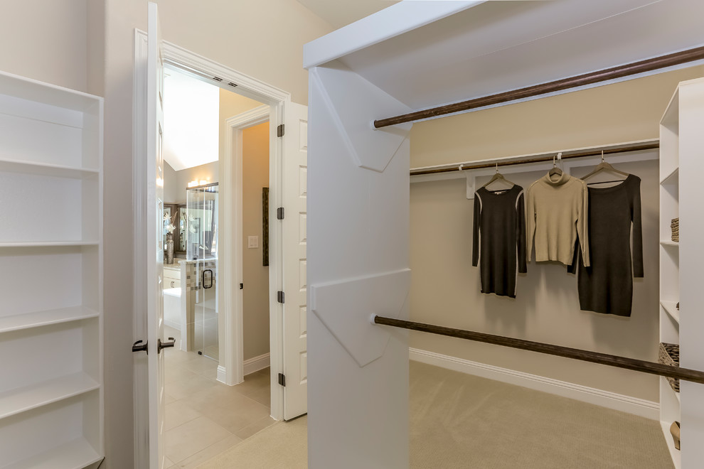 Photo of a large country gender-neutral walk-in wardrobe in Houston with open cabinets, white cabinets, carpet and beige floor.