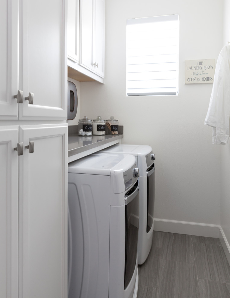 Small transitional galley dedicated laundry room in Sacramento with recessed-panel cabinets, white cabinets, quartz benchtops, white walls, porcelain floors and a side-by-side washer and dryer.