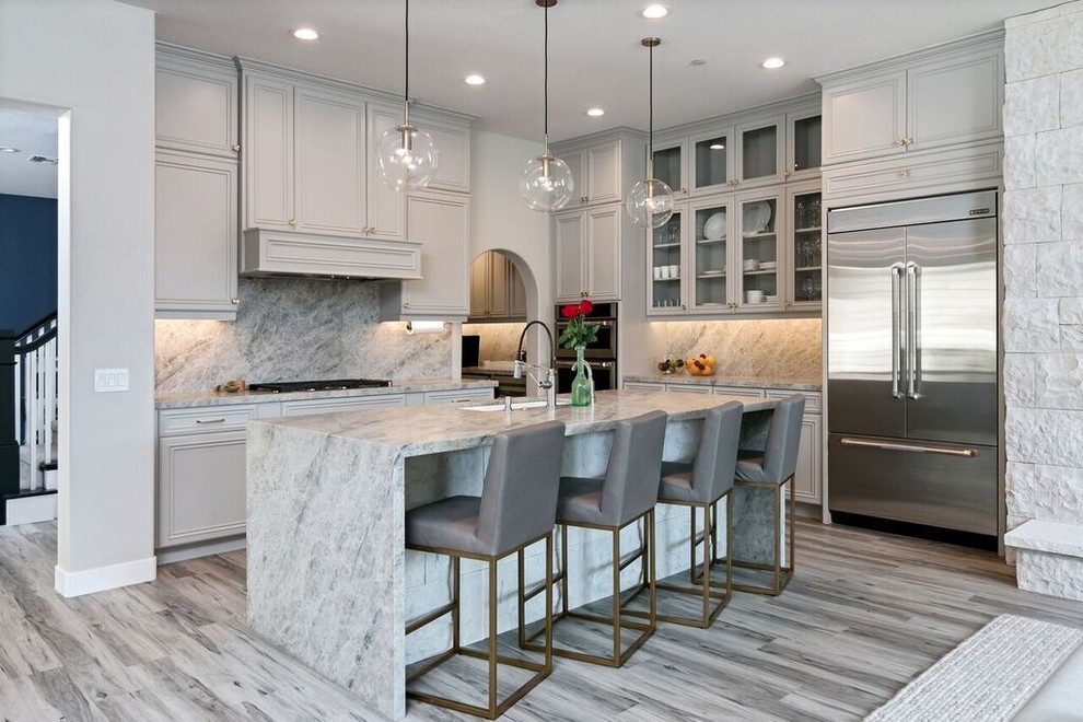 Design ideas for a transitional l-shaped kitchen in Los Angeles with an undermount sink, recessed-panel cabinets, grey cabinets, grey splashback, stainless steel appliances, with island, grey floor, grey benchtop and medium hardwood floors.