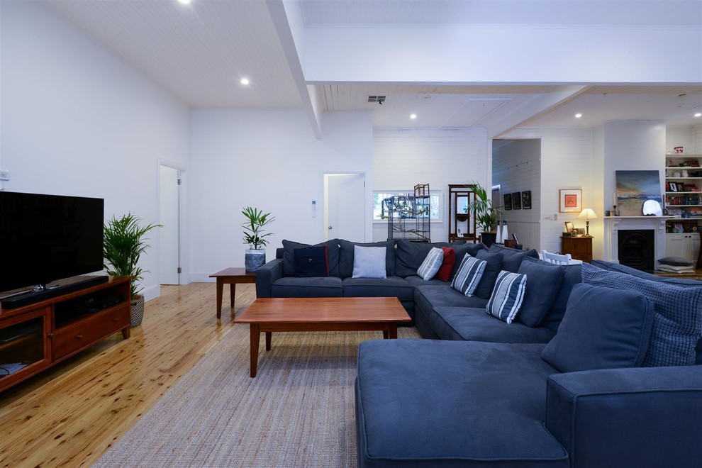 Inspiration for a large traditional open concept living room in Sydney with white walls, light hardwood floors, a corner fireplace, a freestanding tv and brown floor.