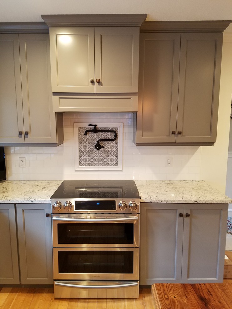 Inspiration for a mid-sized transitional galley light wood floor and brown floor eat-in kitchen remodel with a farmhouse sink, recessed-panel cabinets, gray cabinets, wood countertops, white backsplash, subway tile backsplash, stainless steel appliances and an island