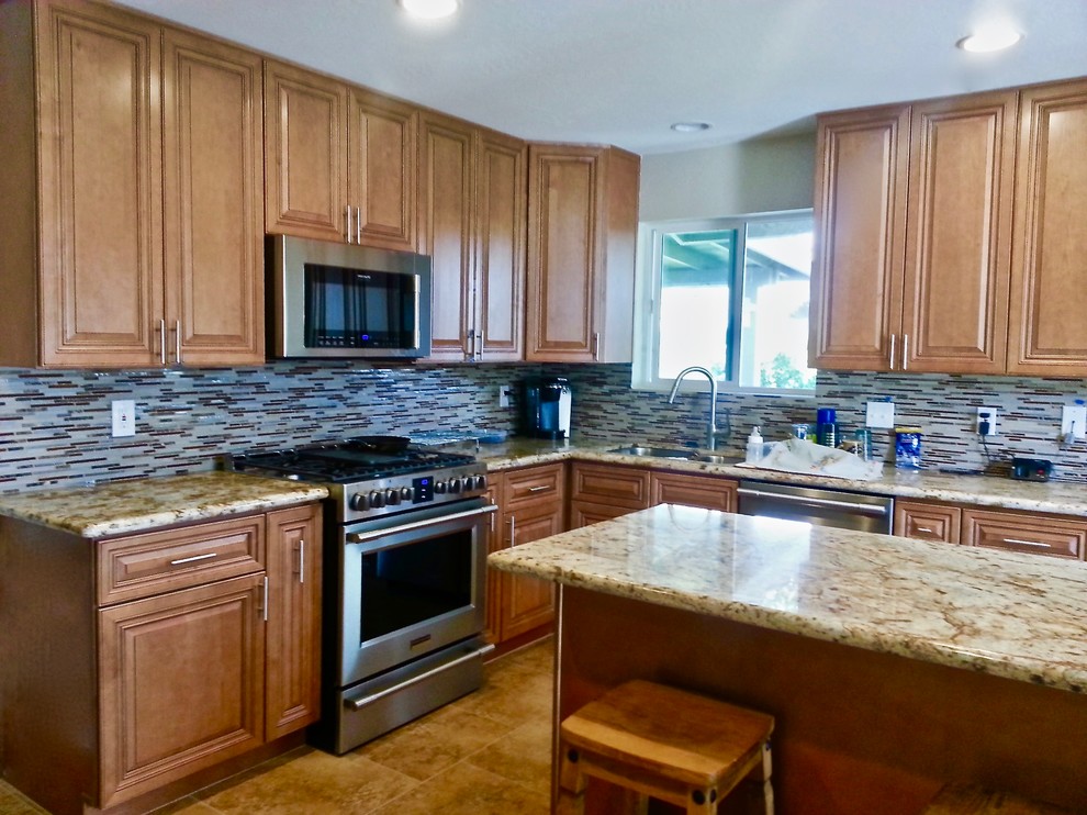 Inspiration for a transitional l-shaped ceramic tile eat-in kitchen remodel in Phoenix with an undermount sink, raised-panel cabinets, medium tone wood cabinets, granite countertops, multicolored backsplash, glass tile backsplash, stainless steel appliances and an island