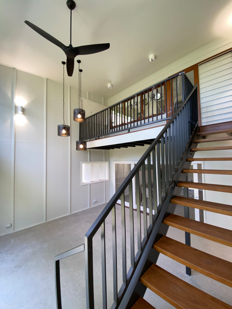 Design ideas for a mid-sized wood staircase in Brisbane with open risers, metal railing and panelled walls.