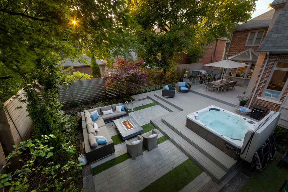 This is an example of a large contemporary backyard rectangular aboveground pool in Toronto with a hot tub and decking.