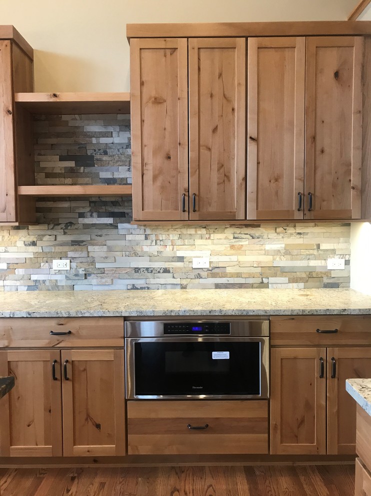 Example of a large mountain style l-shaped medium tone wood floor and brown floor home design design in Chicago with an undermount sink, shaker cabinets, medium tone wood cabinets, granite countertops, green backsplash, slate backsplash, stainless steel appliances, an island and black countertops